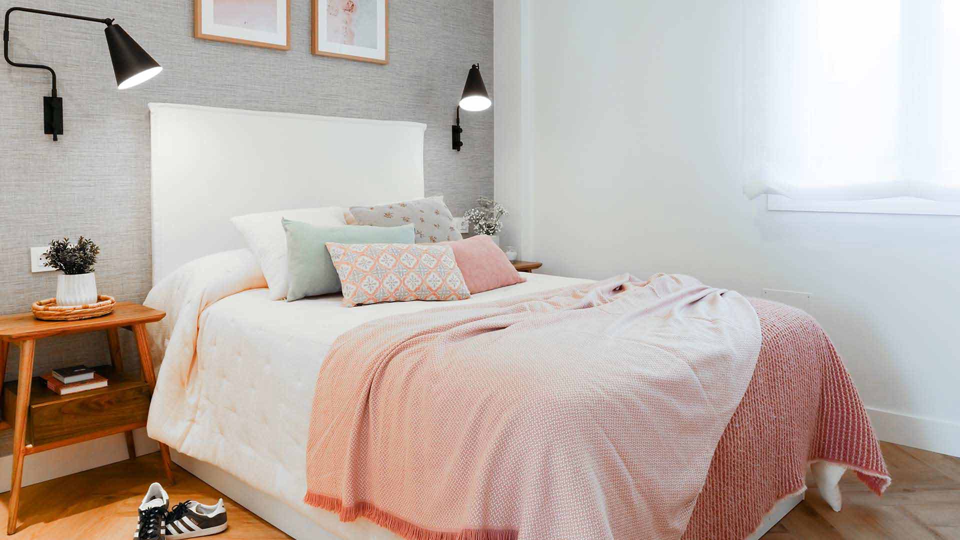 Dormitorio con cama con cabecero tapizado en blanco, papel pintado gris con efecto tejido y mesitas de noche de madera
