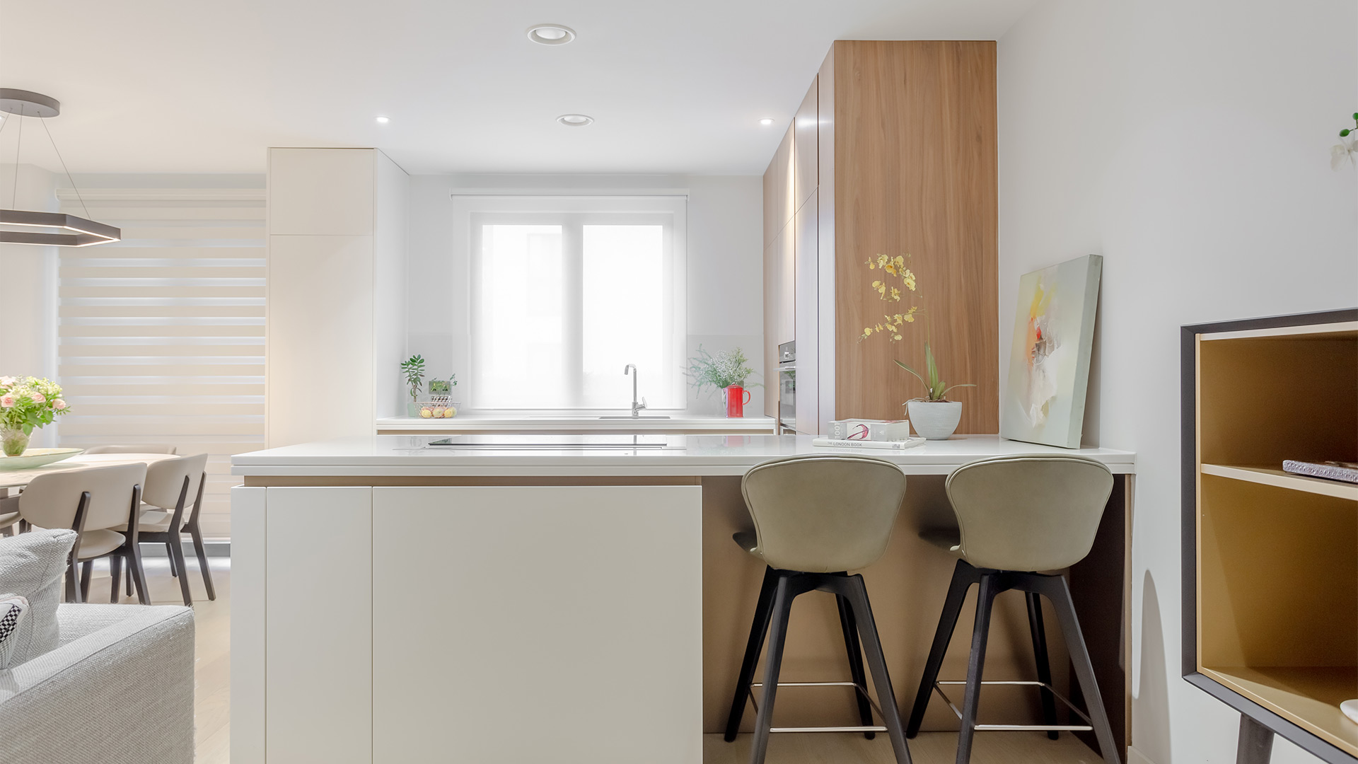 Cocina moderna con isla central, taburetes beige y decoración minimalista en tonos neutros.